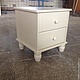 White bedside table with two drawers and square top, which can accommodate a lamp, clock and favorite book.