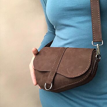 женская рука держит сумку-седло из замши на улице города